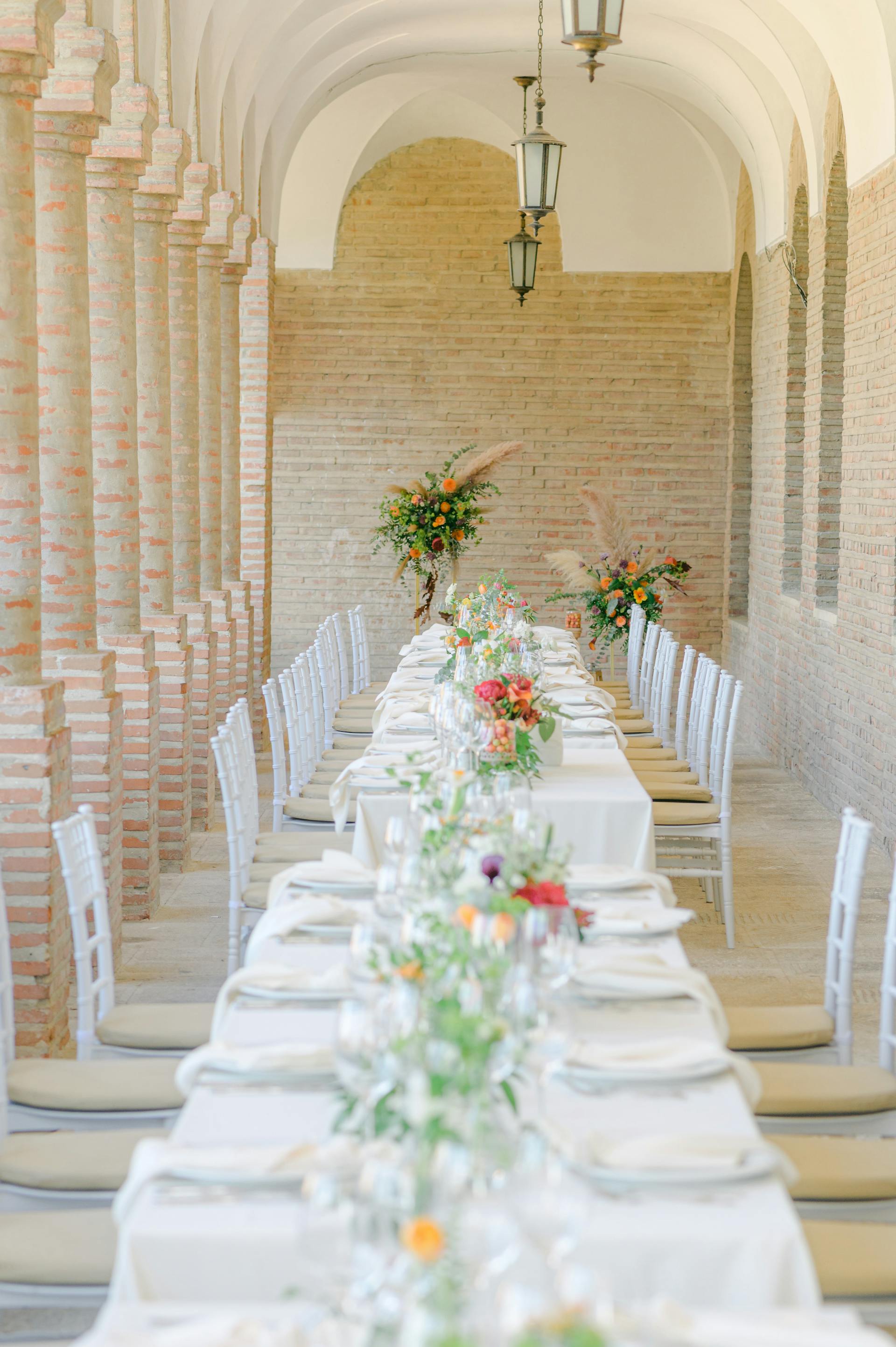 Table de mariage longue avec chemin végétal bas, nappe de lin écru froissé.